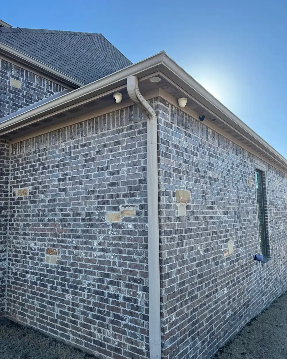 Outdoor security camera mounted on the corner of a brick home